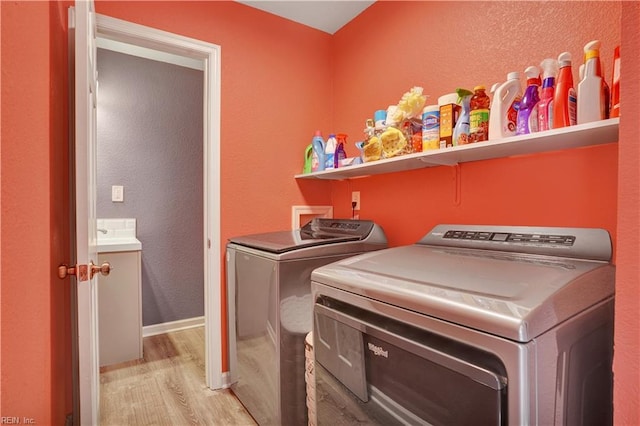 clothes washing area with washing machine and clothes dryer, laundry area, baseboards, and wood finished floors