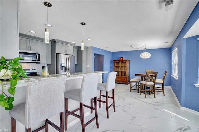 kitchen with marble finish floor, gray cabinets, stainless steel appliances, and a textured ceiling