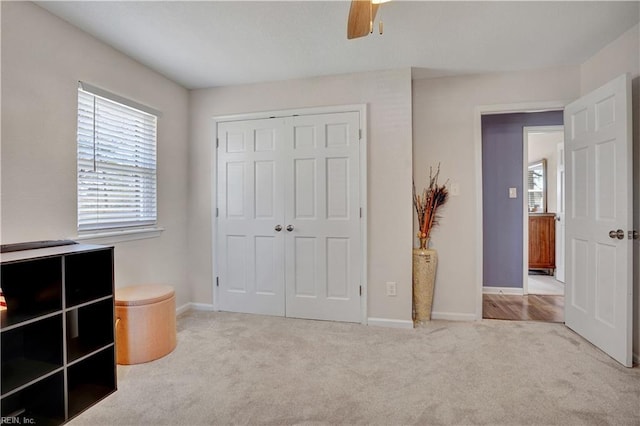 unfurnished bedroom featuring a ceiling fan, carpet, a closet, and baseboards