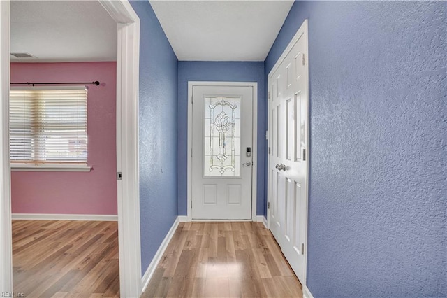 entryway with baseboards, wood finished floors, and a textured wall