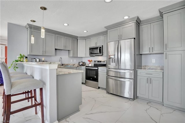 kitchen featuring marble finish floor, appliances with stainless steel finishes, a peninsula, and gray cabinetry