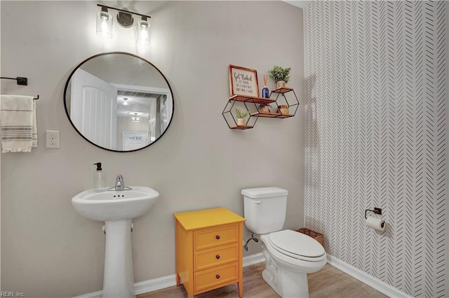 bathroom with toilet, wood finished floors, and baseboards