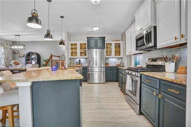 kitchen with a kitchen bar, light wood-style flooring, a sink, backsplash, and stainless steel appliances