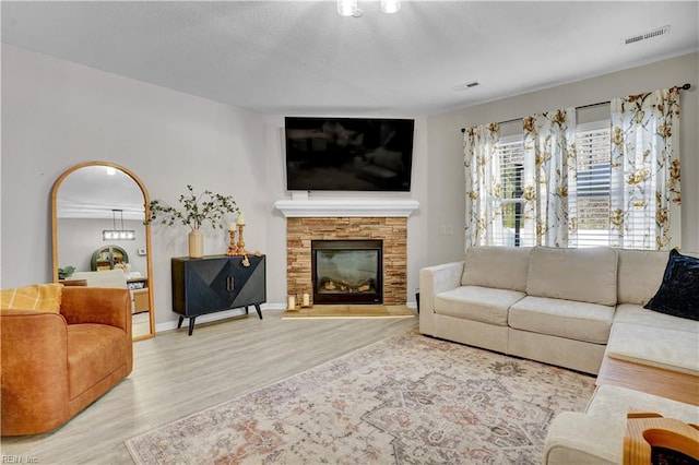 living area with visible vents, a textured ceiling, wood finished floors, arched walkways, and a stone fireplace