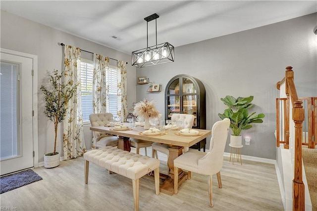 dining area with arched walkways, visible vents, light wood-style flooring, and baseboards