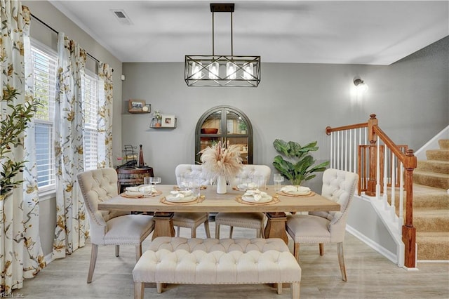 dining room featuring visible vents, baseboards, light wood-style flooring, and stairs