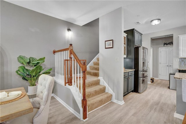 stairway with visible vents, wood finished floors, and baseboards