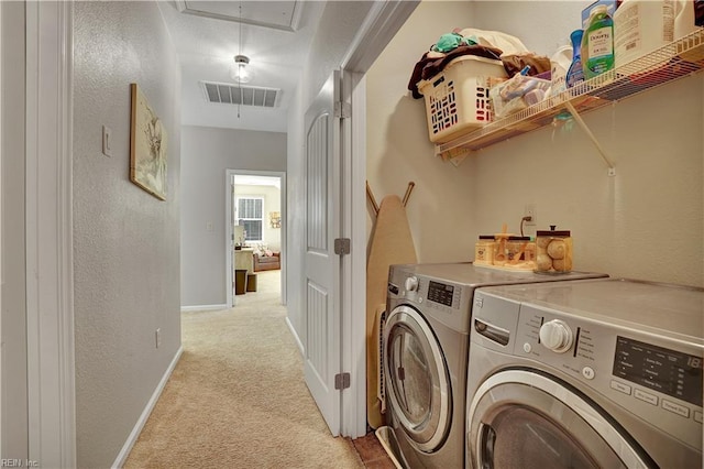 clothes washing area featuring visible vents, washing machine and dryer, light colored carpet, attic access, and laundry area