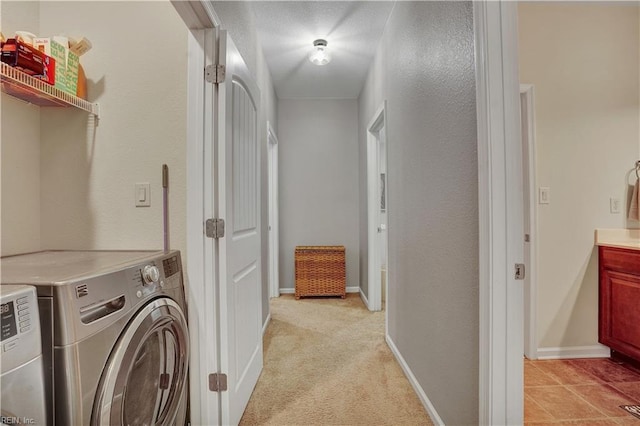 clothes washing area featuring laundry area, light colored carpet, baseboards, and washing machine and clothes dryer