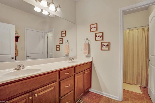 bathroom featuring a sink, baseboards, double vanity, and tile patterned floors