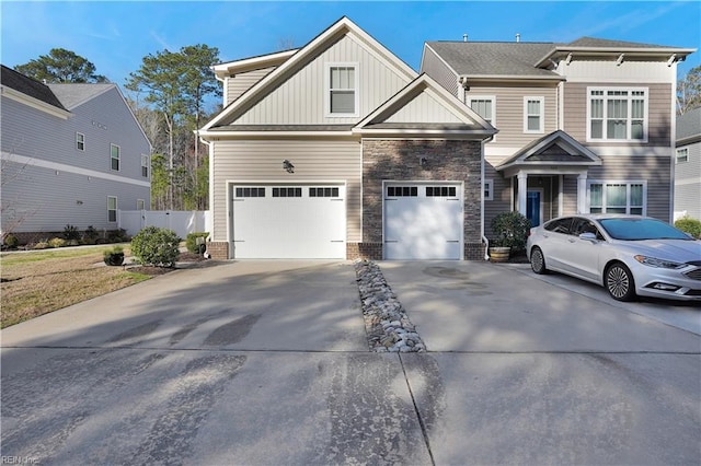 view of front of house with fence, concrete driveway, a garage, stone siding, and board and batten siding