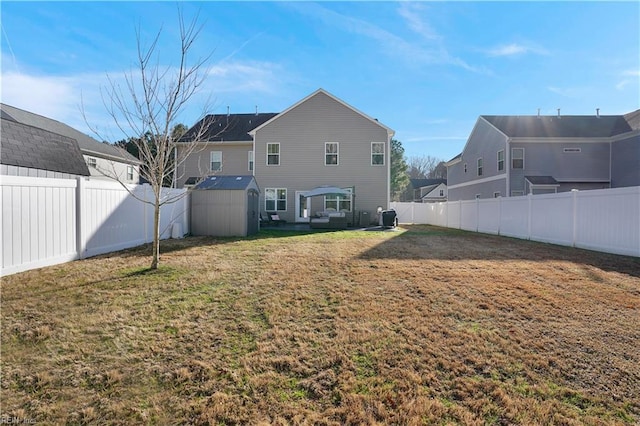 back of property with a shed, a yard, a fenced backyard, an outdoor structure, and a residential view