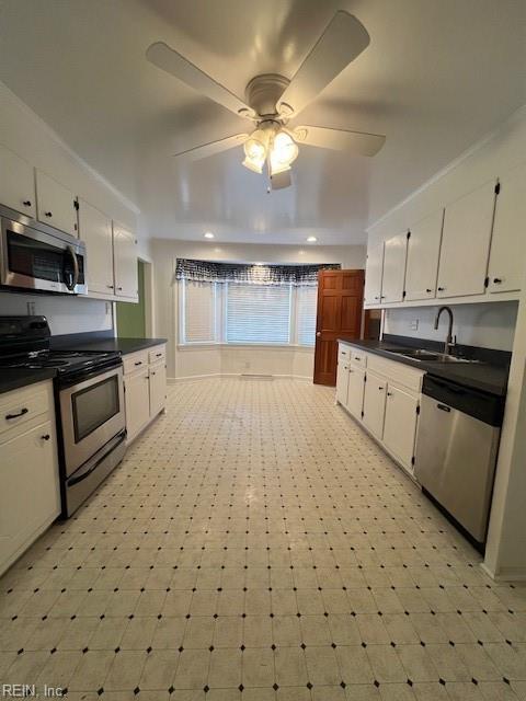 kitchen with a sink, dark countertops, white cabinets, and stainless steel appliances