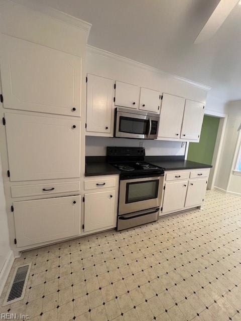 kitchen with dark countertops, visible vents, appliances with stainless steel finishes, and ornamental molding