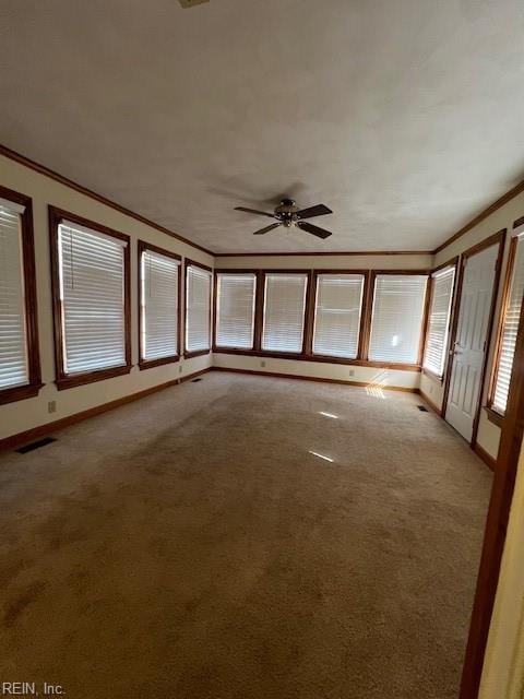 empty room with visible vents, light carpet, crown molding, baseboards, and ceiling fan