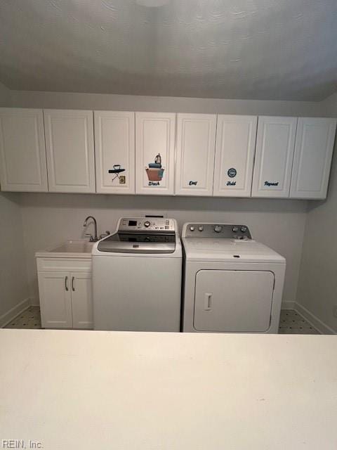 washroom with washing machine and clothes dryer, cabinet space, baseboards, and a sink