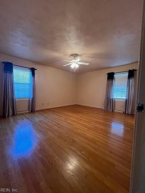 empty room with a ceiling fan, wood finished floors, and baseboards