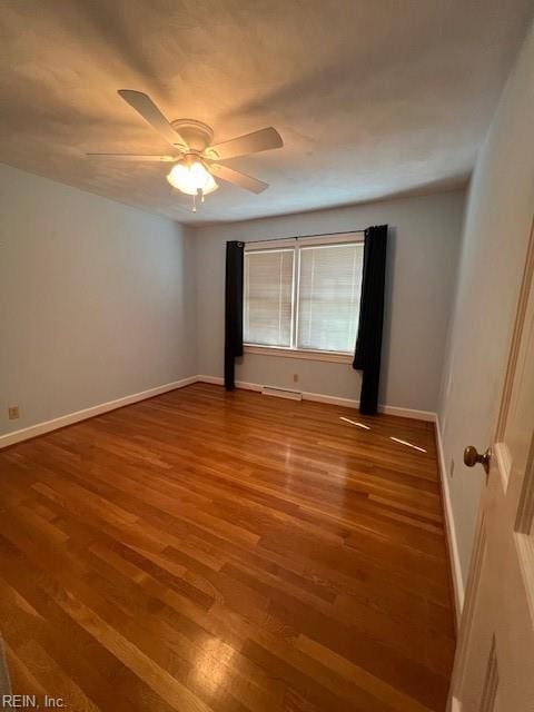 spare room featuring wood finished floors, baseboards, and ceiling fan