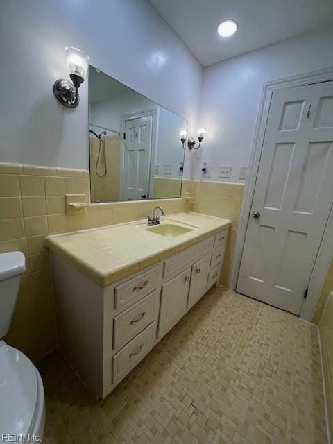 bathroom with vanity, tile walls, toilet, and a wainscoted wall