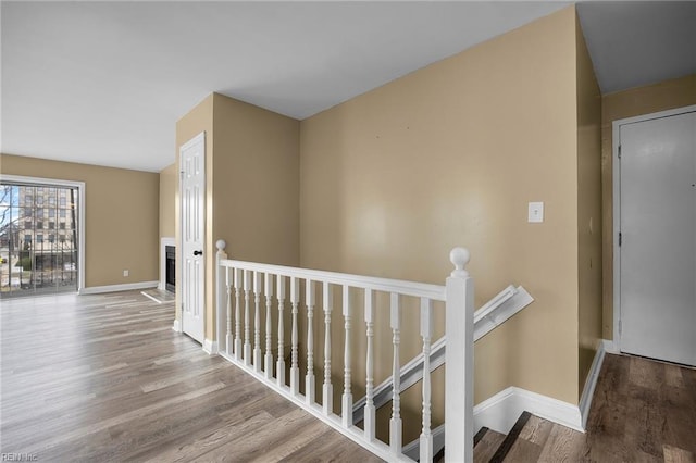 corridor featuring an upstairs landing, baseboards, and wood finished floors