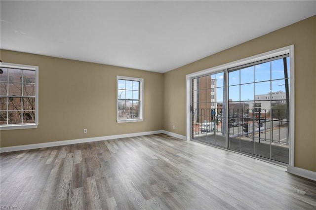 spare room with baseboards and wood finished floors