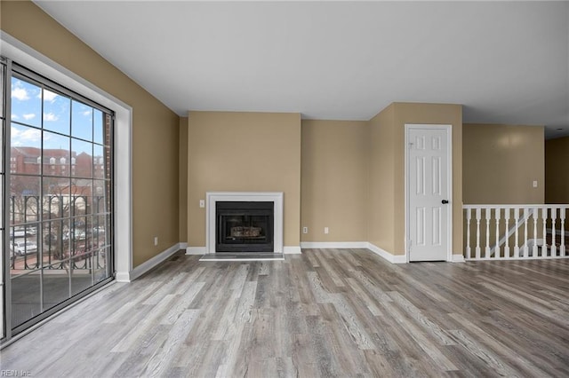 unfurnished living room with baseboards, wood finished floors, and a fireplace