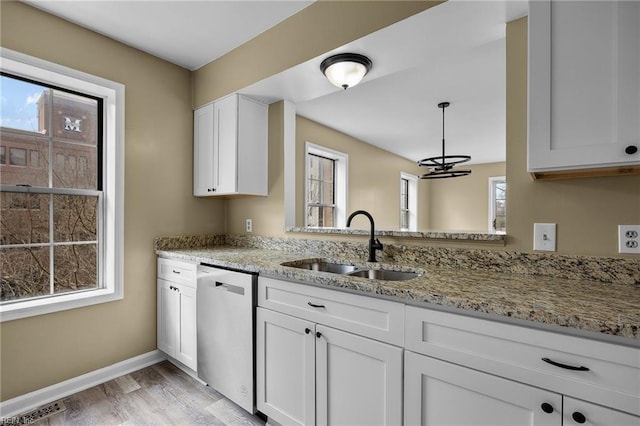 kitchen featuring light stone counters, visible vents, light wood finished floors, a sink, and stainless steel dishwasher