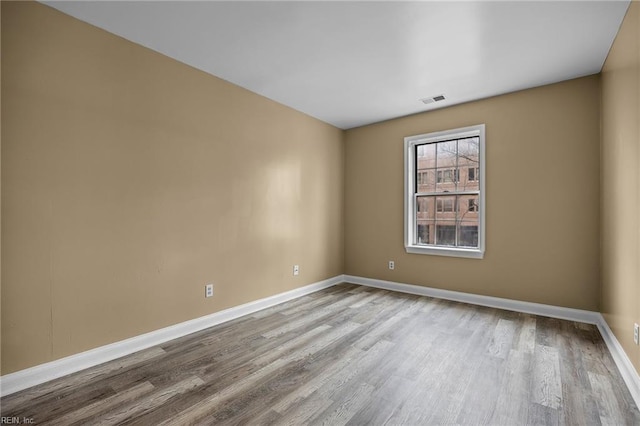 unfurnished room featuring wood finished floors, visible vents, and baseboards