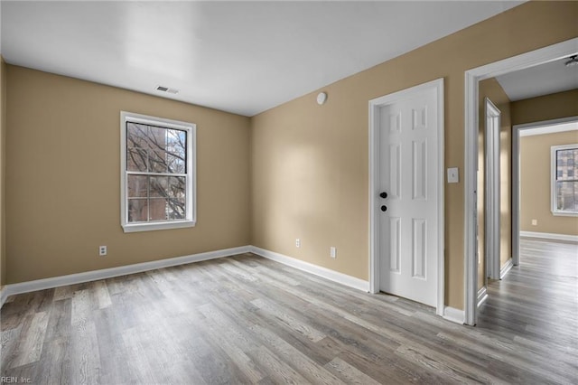 empty room with visible vents, baseboards, and wood finished floors