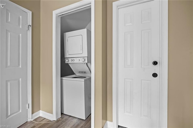 washroom with baseboards, dark wood finished floors, laundry area, and stacked washer / dryer