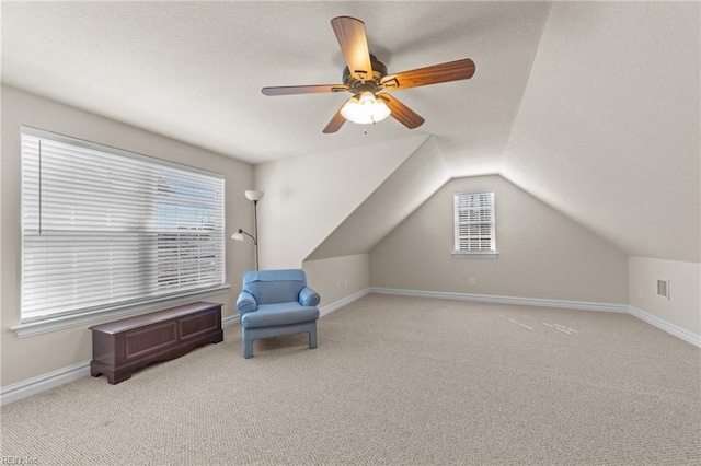 living area featuring a textured ceiling, lofted ceiling, baseboards, and light carpet