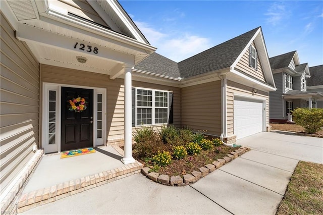 entrance to property featuring a garage, driveway, and a shingled roof