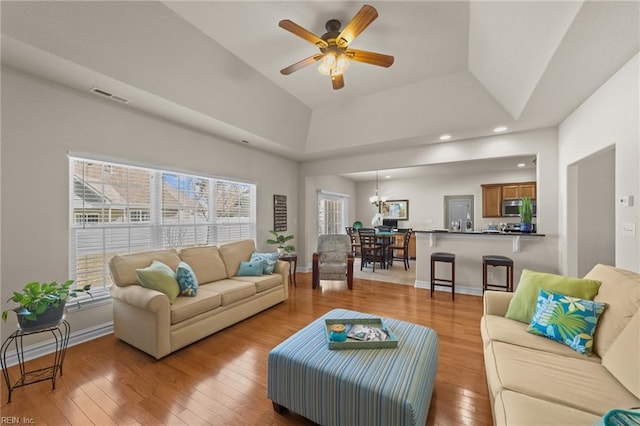 living room with visible vents, wood-type flooring, a healthy amount of sunlight, and ceiling fan with notable chandelier