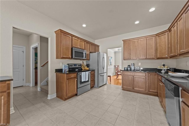 kitchen featuring dark stone counters, recessed lighting, brown cabinetry, and appliances with stainless steel finishes