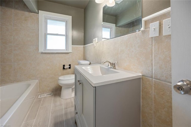 full bath with tile walls, a healthy amount of sunlight, a bath, and toilet