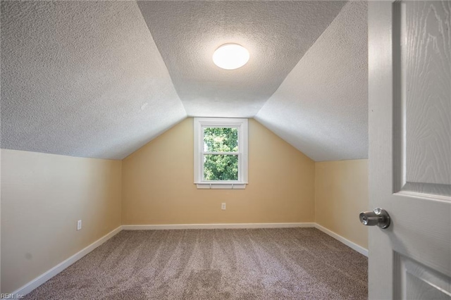 additional living space featuring vaulted ceiling, a textured ceiling, baseboards, and carpet floors