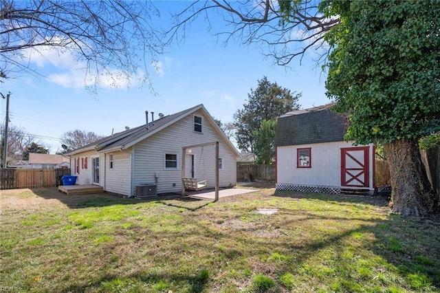 rear view of property featuring an outbuilding, central AC unit, a shed, a fenced backyard, and a lawn