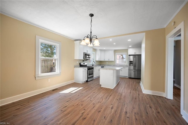 kitchen with dark wood-style floors, baseboards, white cabinets, appliances with stainless steel finishes, and a center island