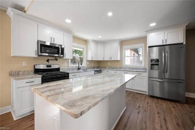 kitchen with white cabinetry, light stone countertops, dark wood-style flooring, and appliances with stainless steel finishes