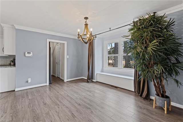 unfurnished dining area featuring crown molding, baseboards, light wood finished floors, and a chandelier