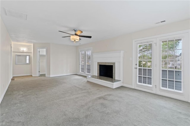 unfurnished living room featuring visible vents, a ceiling fan, a high end fireplace, carpet floors, and baseboards