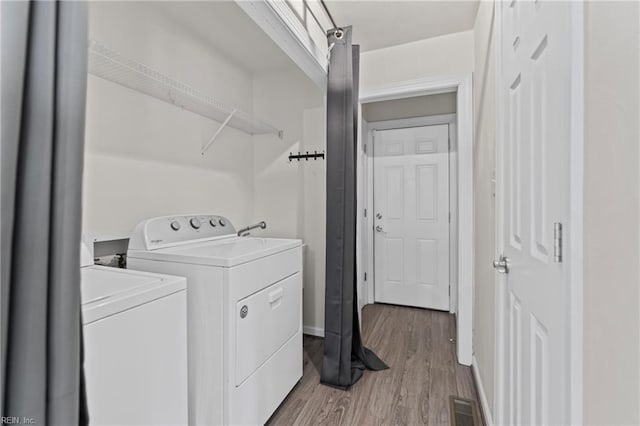 washroom with visible vents, baseboards, laundry area, light wood-style floors, and washer and dryer