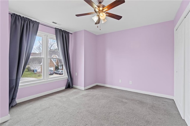 carpeted empty room featuring visible vents, baseboards, and a ceiling fan