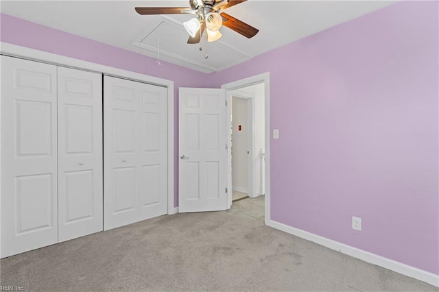 unfurnished bedroom with baseboards, attic access, ceiling fan, a closet, and carpet flooring