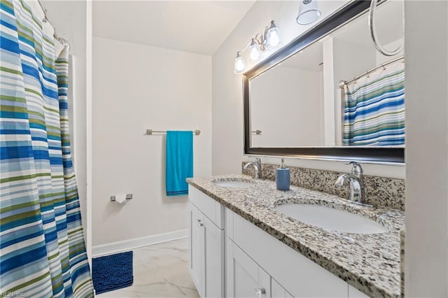 full bathroom featuring double vanity, marble finish floor, baseboards, and a sink