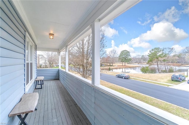 wooden deck featuring a water view and a porch