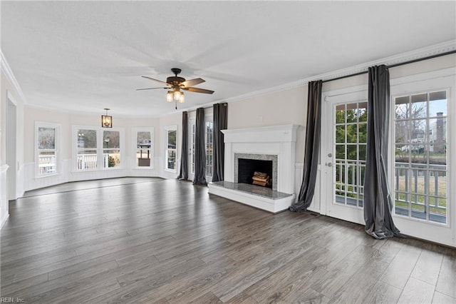 unfurnished living room featuring a wealth of natural light, a ceiling fan, wood finished floors, and crown molding