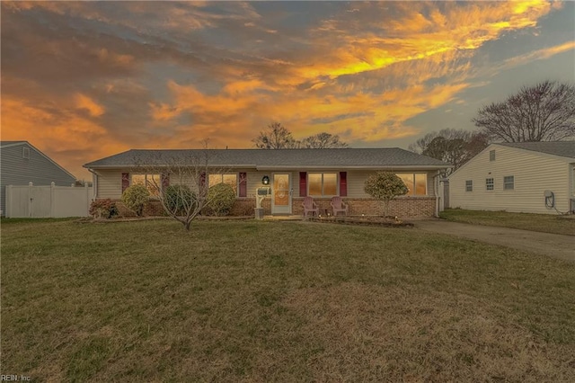 single story home featuring driveway, a lawn, brick siding, and fence