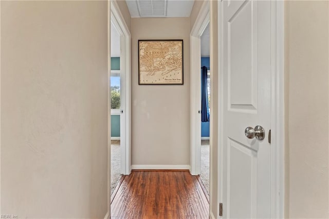 corridor featuring dark wood-type flooring, baseboards, and visible vents