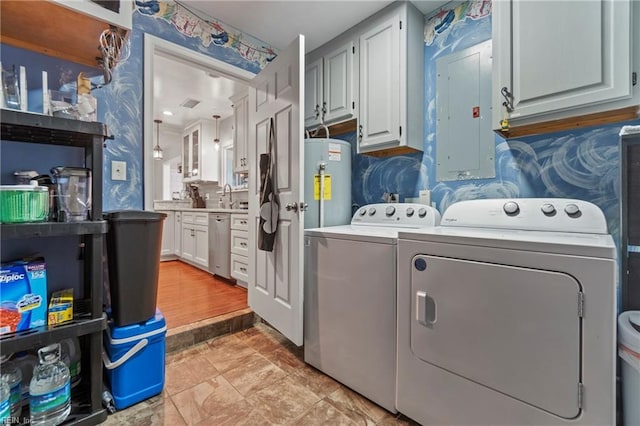 clothes washing area with electric panel, a sink, washing machine and dryer, water heater, and cabinet space